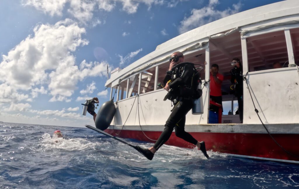 Alle Maldive, n subacqueo entra in acqua dal Dhoni con il passo del gigante.