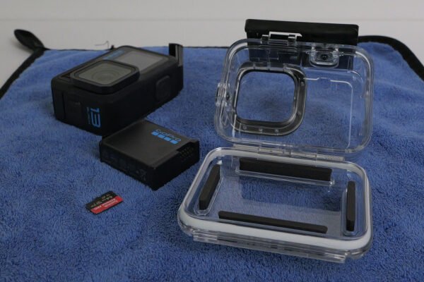 Questa foto mostra una custodia originale GoPro aperta dopo l'imemrisone, si vedono anch ela GoPro Hero13, la batteria e la scheda microSD